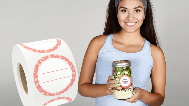 a woman holding a jar of food next to a roll of dissolvable labels