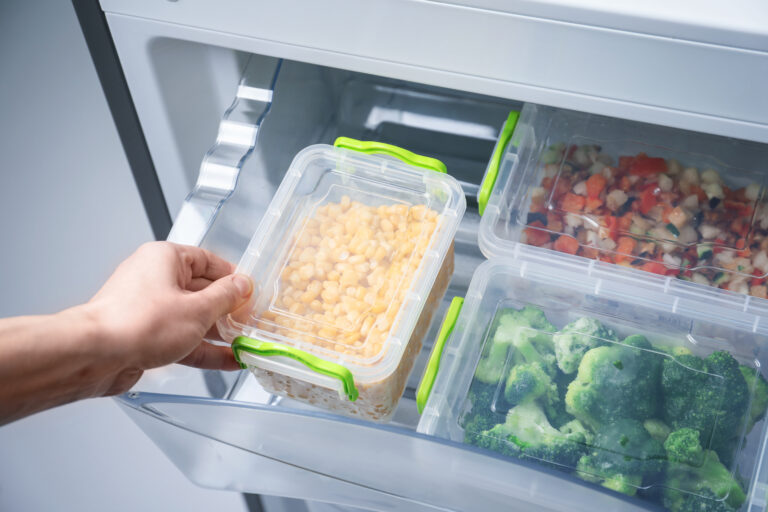 a person taking a container of food out of a refrigerator.