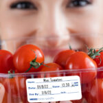 a woman holding a container of tomatoes in front of her face.