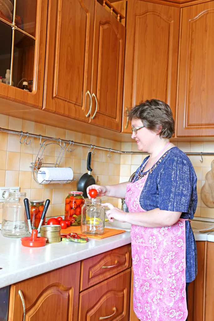 Woman housewife engaged in canning vegetables in the kitchen